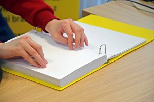 Knjiga v brajici, ki jo oseba bere z obema rokama