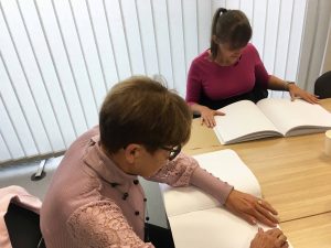 Udeleženki usposabljanja ob branju brajevega priročnika