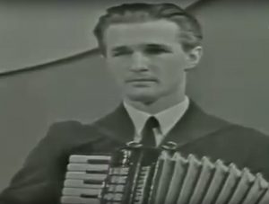 na sliki je moški, ki igra harmoniko. Fotografija sodi v 60-leta prejšnjega stoletja.