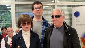 3 osebe do višine pasu, obrnjene proti nam. Desno g. Kermc, levo nagrajenka Danica Bakovnik. Oba imata temna očala. V sredini Luka Pavlin, voditelj dogodka.